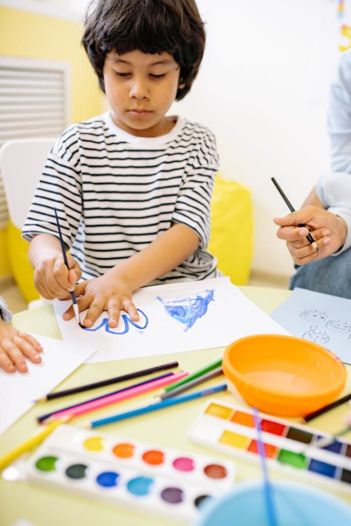 pexels-photo-8612982 Child using watercolors and colored pencils for a creative drawing session at home.